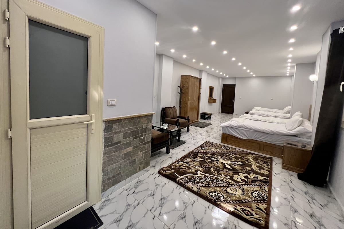 Moderni hotellihuone, jossa on suuri sänky, oleskelualue, vaatekaappi ja kylpyhuone.