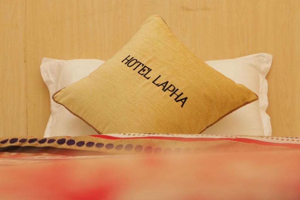 A bed with a pillow labeled "HOTEL LAPHA" and a polka-dotted bedspread.