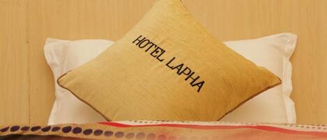 A bed with a pillow labeled "HOTEL LAPHA" and a polka-dotted bedspread.