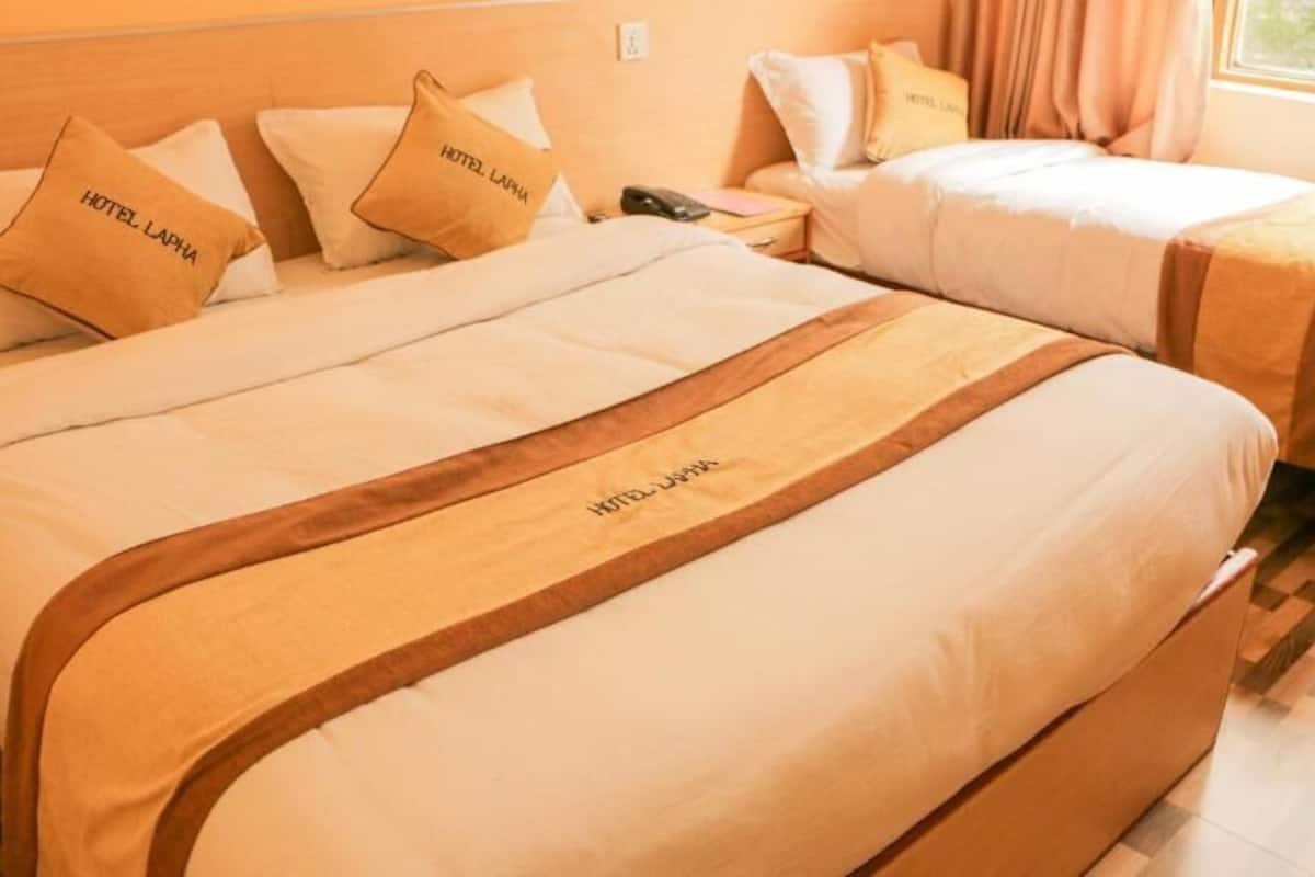 A hotel room with two beds, each with a headboard and pillows labeled "HOTEL LAPHA".
