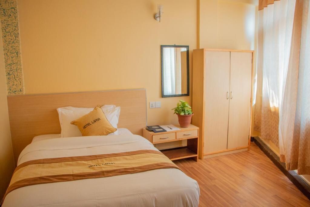 Une chambre d’hôtel avec un lit, une table de chevet, une armoire et un miroir au mur.