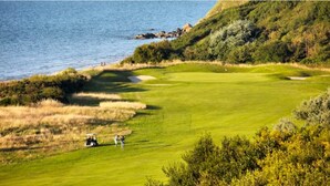 Um campo de golfe com um corpo de água ao fundo.