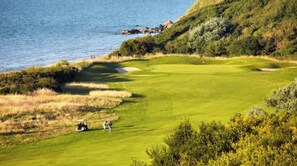 Een golfbaan met een waterpartij op de achtergrond.
