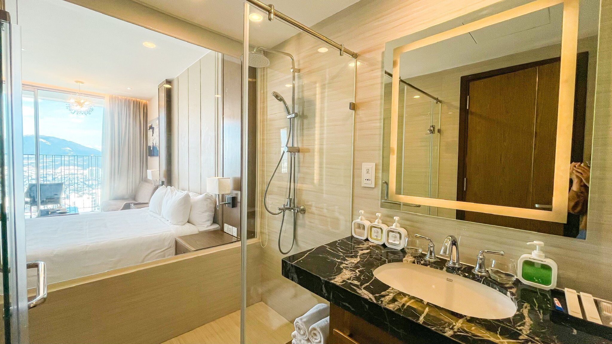 A hotel bathroom with a large mirror, a bathtub, a shower, and a sink with toiletries.