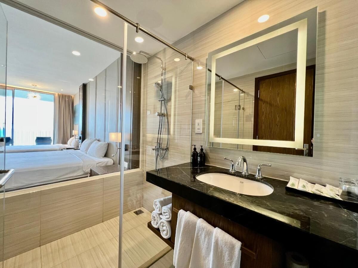 A modern hotel bathroom with a large mirror, a bathtub, and a shower.