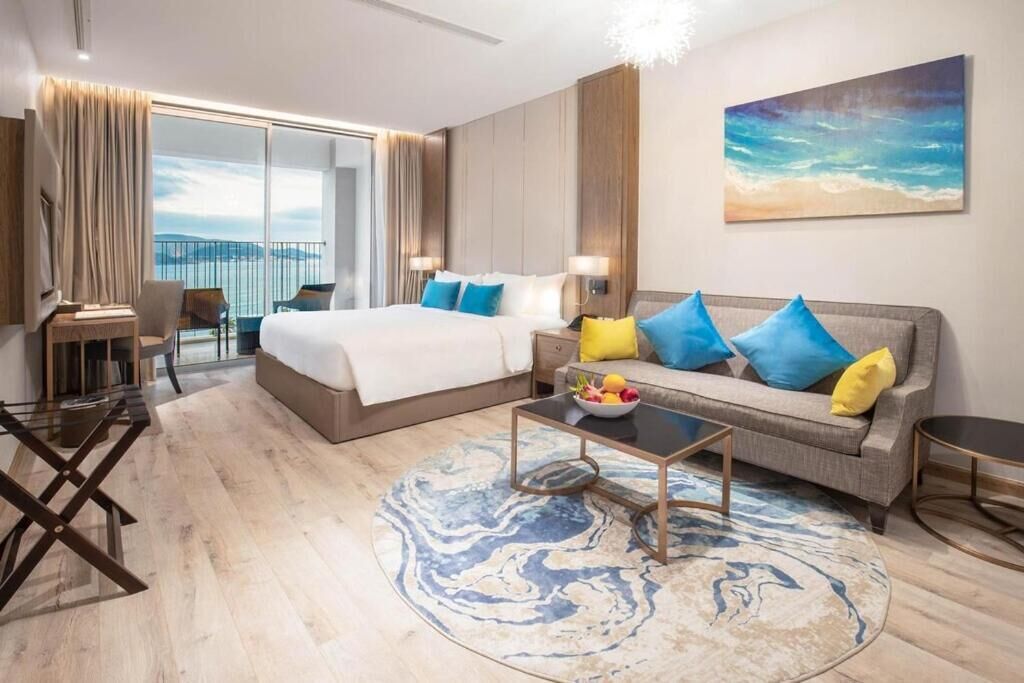 Ein modernes Hotelzimmer mit einem großen Bett, einer Couch, einem Couchtisch und Meerblick.