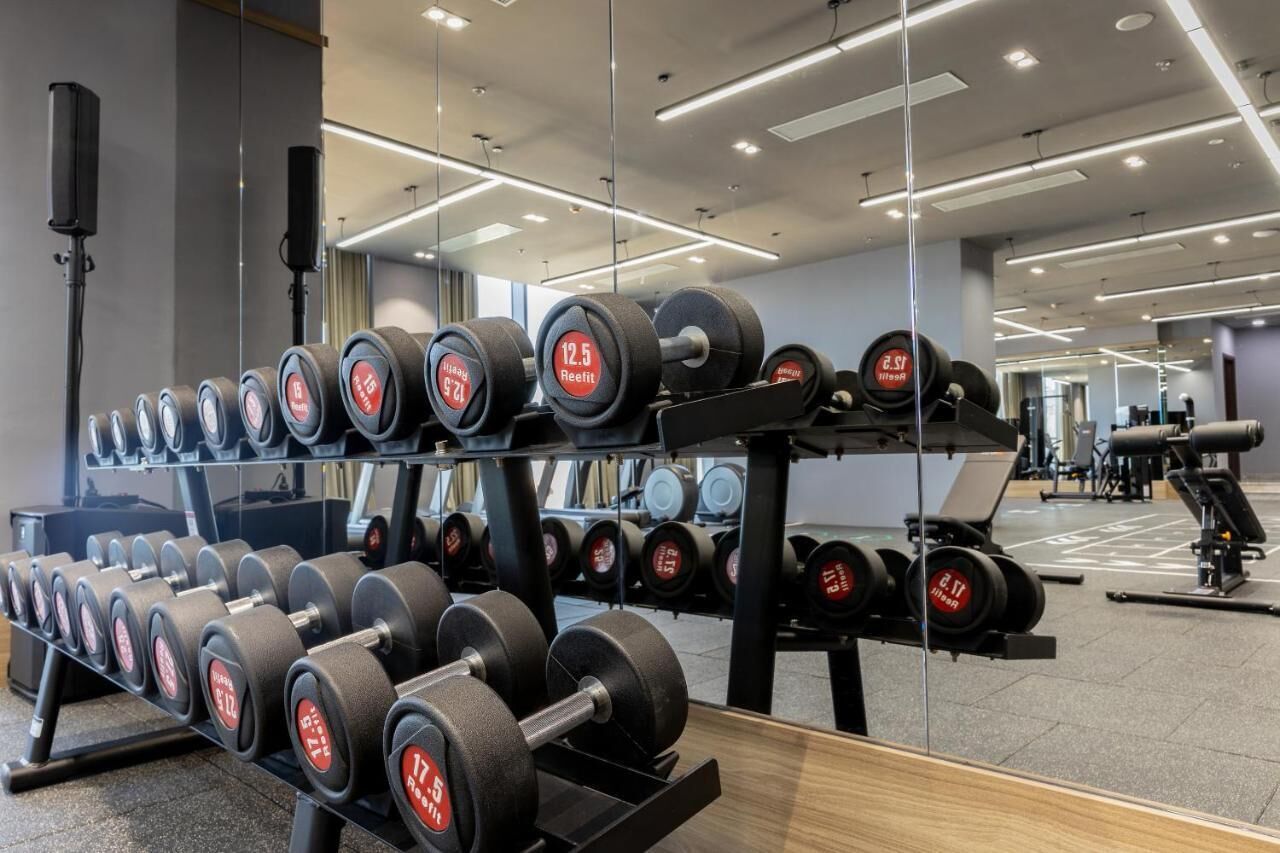 A gym with weightlifting equipment, including dumbbells and barbells, arranged on racks.