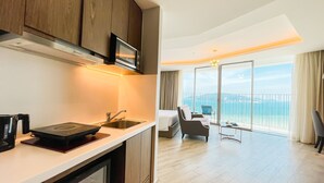 Una habitación de hotel moderna con cocina, un balcón y vistas a la ciudad, además de un ventanal grande.