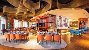 Un restaurante espacioso con varias zonas de comedor, suelo de madera y una barra central.