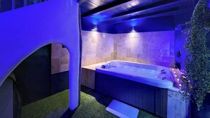 Un área de spa con un jacuzzi, paredes de piedra e iluminación azul.