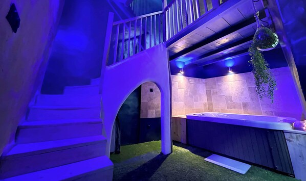 Un espace de détente avec un mur en pierre, une petite arche et une plante suspendue.