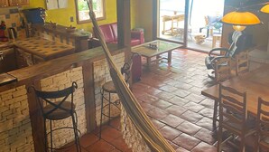 A cozy interior with a hammock, a kitchen area, and a dining space with chairs and a table. - Character villa for rent (Le Roc)