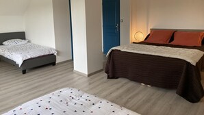 Un dormitorio con dos camas, una puerta azul y una lámpara de noche.
