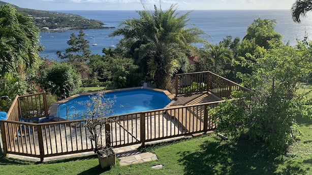 A swimming pool with a wooden deck and a view of the ocean.