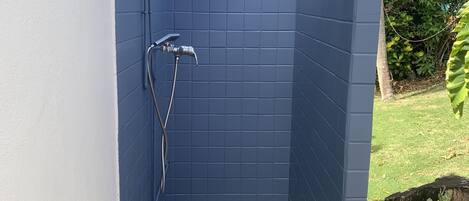 A small, enclosed shower area with a tiled blue interior and a green mat at the entrance.
