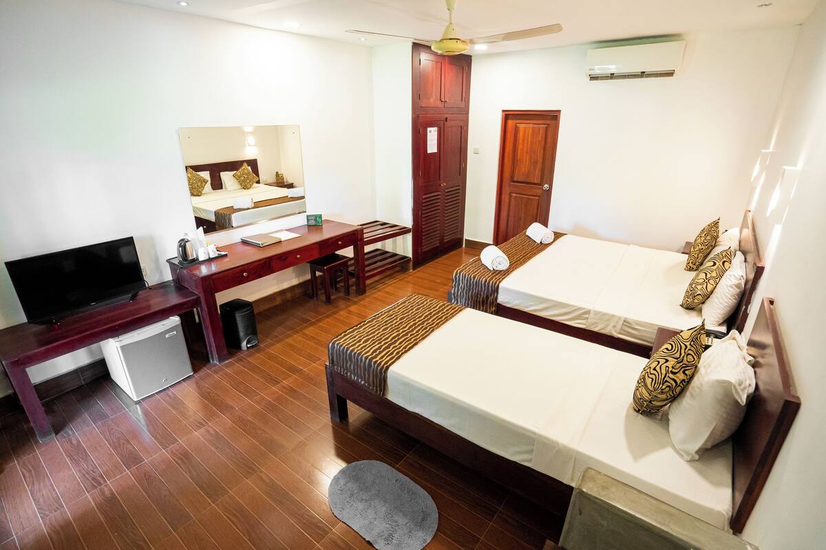 A hotel room with a bed, a desk, a television, and a small refrigerator.