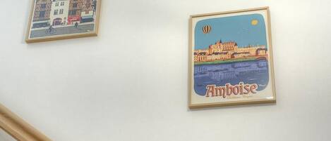 Two framed posters on a wall, one depicting a town scene and the other a cityscape with a hot air balloon.