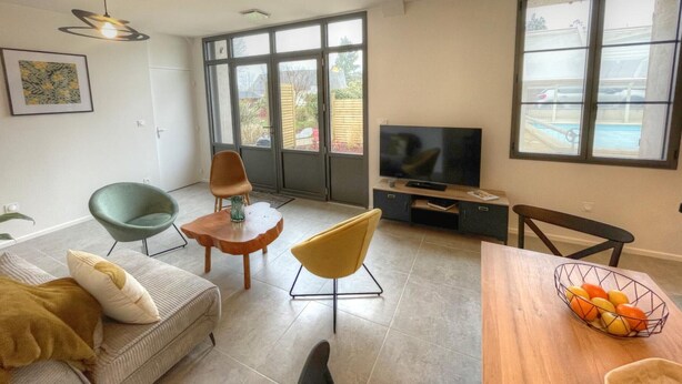 A modern living room with a sofa, two chairs, a TV, and a dining table with fruit. - Charming Gîte with Private Pool near Amboise, Sleeps 5, Fully Equipped (Saint-Règle)