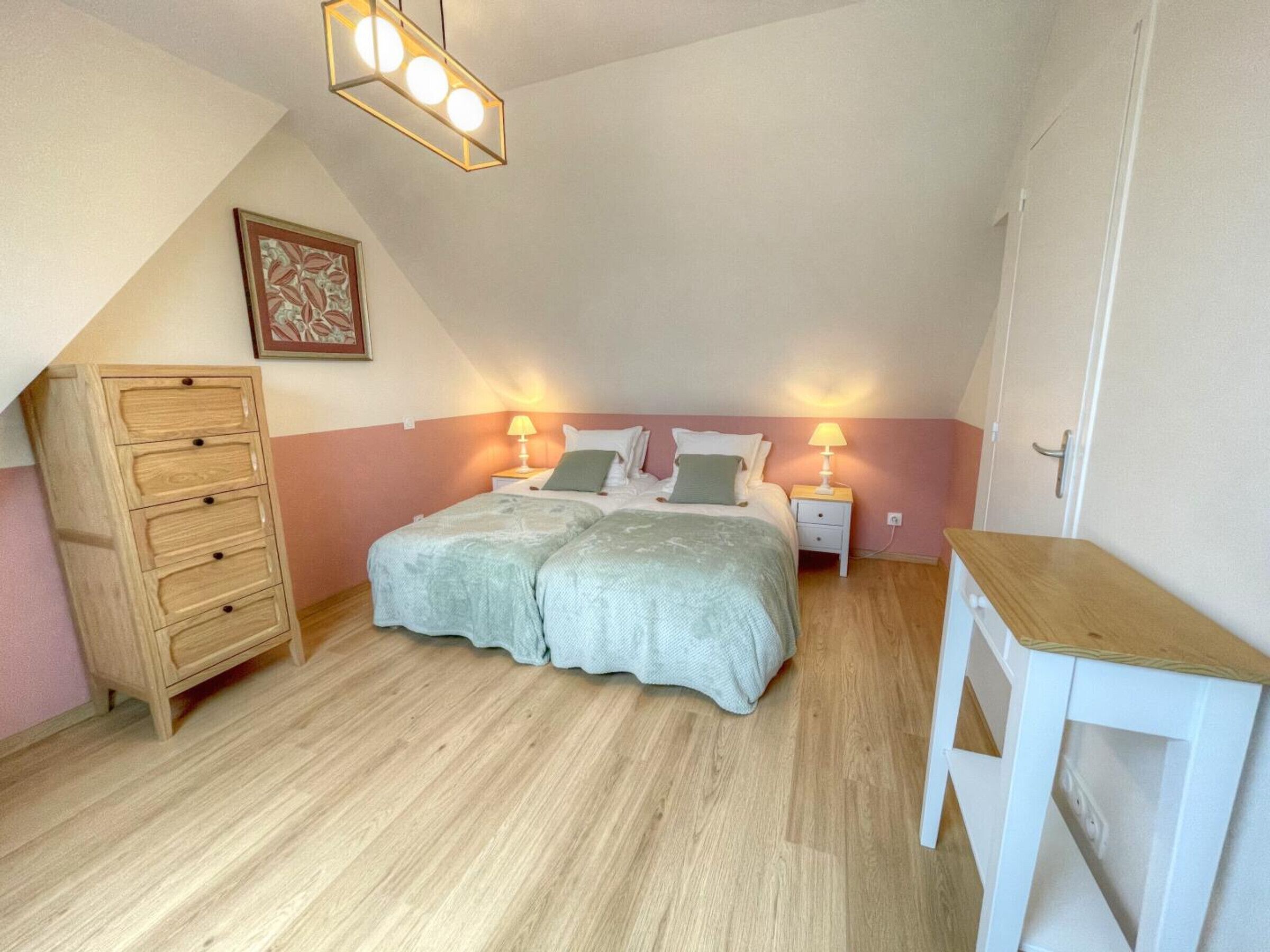 A bedroom with a bed, two bedside tables, a dresser, and a ceiling light fixture.