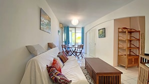 Ein gemütliches Wohnzimmer mit einer Couch, einem Holztisch und einem Essbereich mit Stühlen und Tisch.