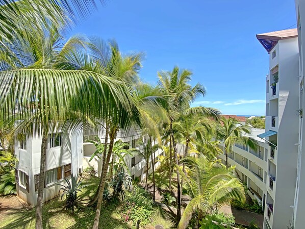 A resort with multiple-story buildings, palm trees, and a clear blue sky.