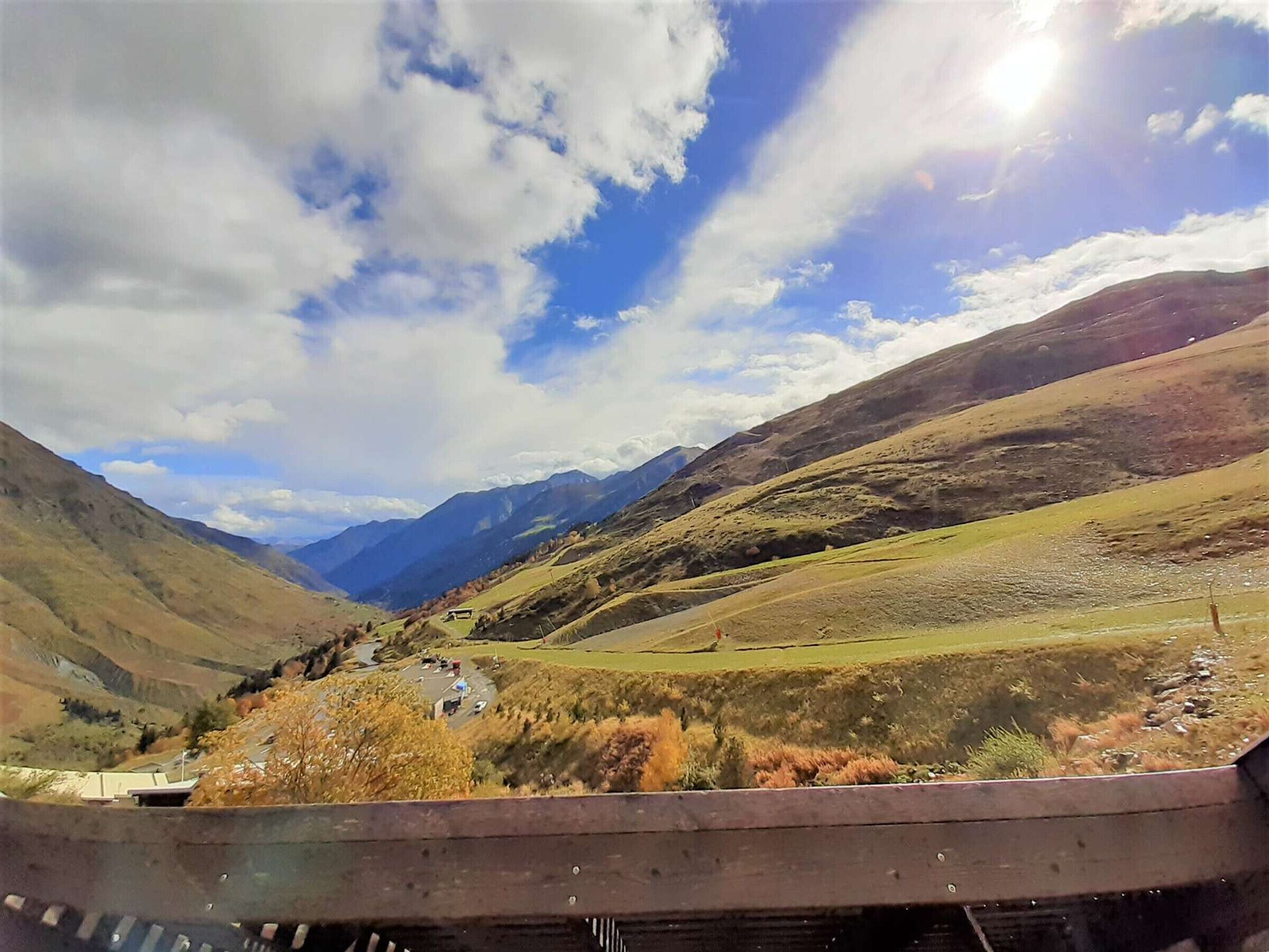 Une vallée avec des montagnes en arrière-plan, un ciel dégagé et une structure en bois au premier plan.