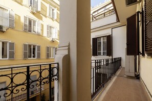 Un couloir étroit doté de balcons, un mur blanc et une rambarde en métal noir.