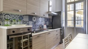 A modern kitchen with a built-in oven, stainless steel appliances, and patterned backsplash tiles.