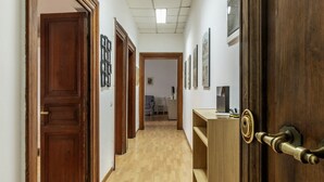 A hallway with wooden doors, a wooden desk, and framed pictures on the walls.