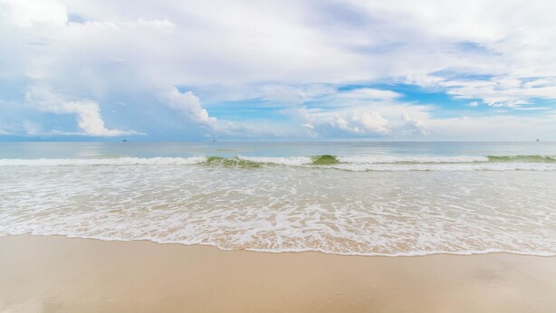 A beach with waves gently lapping onto the shore under a partly cloudy sky. - DUNES 102, 1/2 1st Floor, No Elevator, Sea South Properties (Gulf Shores)