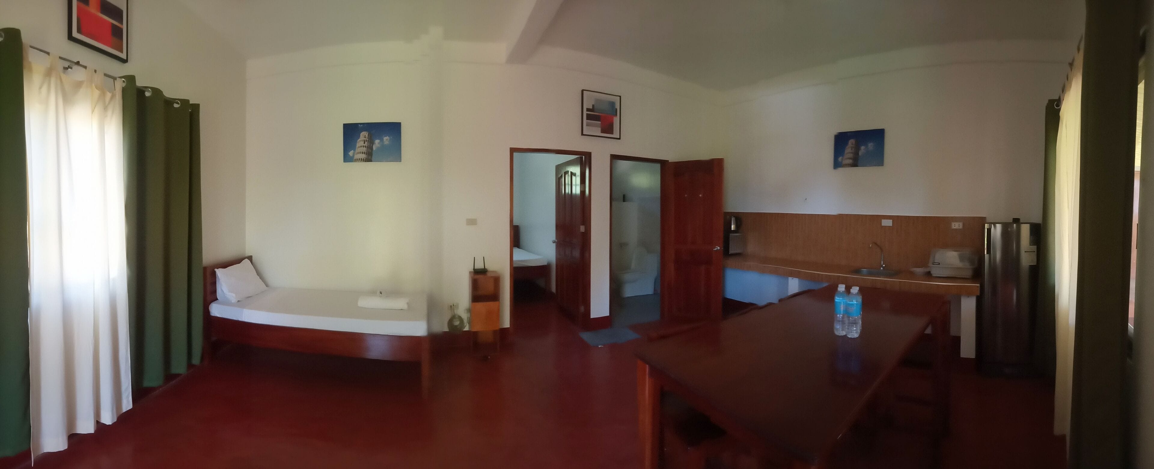 Een kamer met een bed, een houten tafel, een kitchenette en een badkamer.