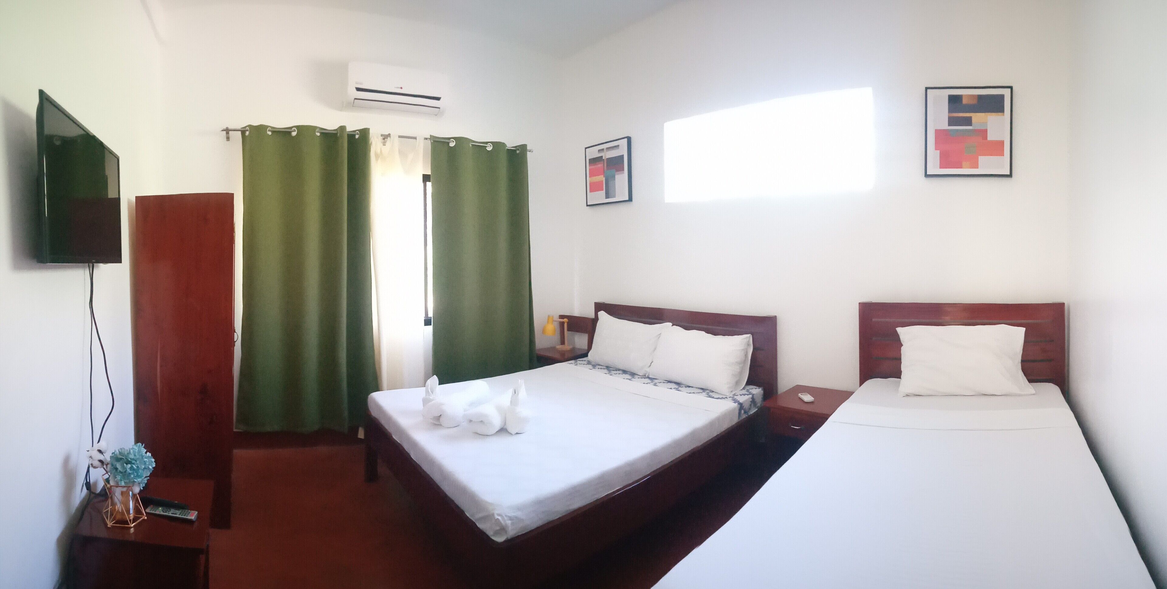 Habitación de hotel con dos camas, televisor, aire acondicionado y una ventana con cortinas.