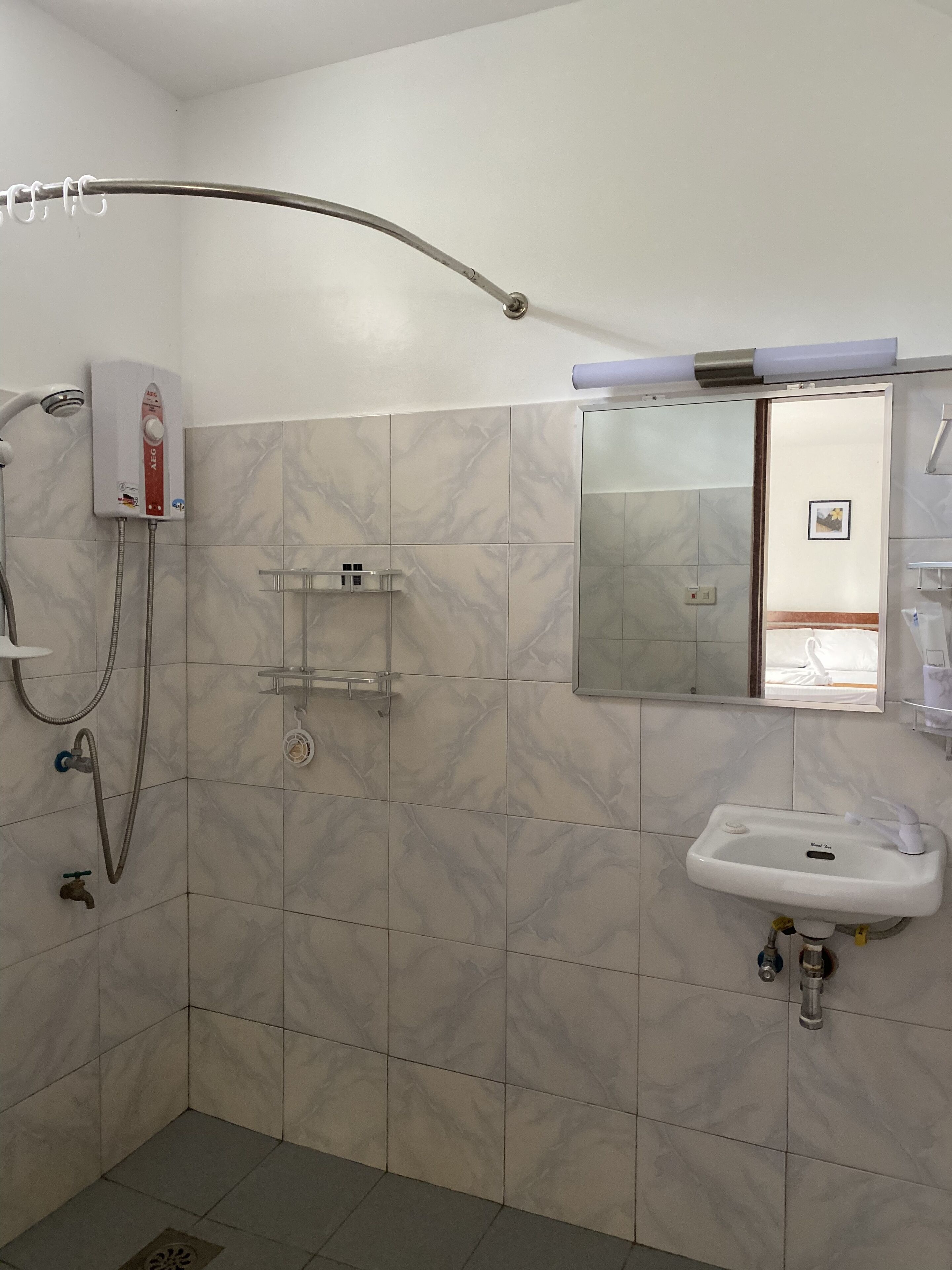 A bathroom with a shower, a sink, and a mirror.
