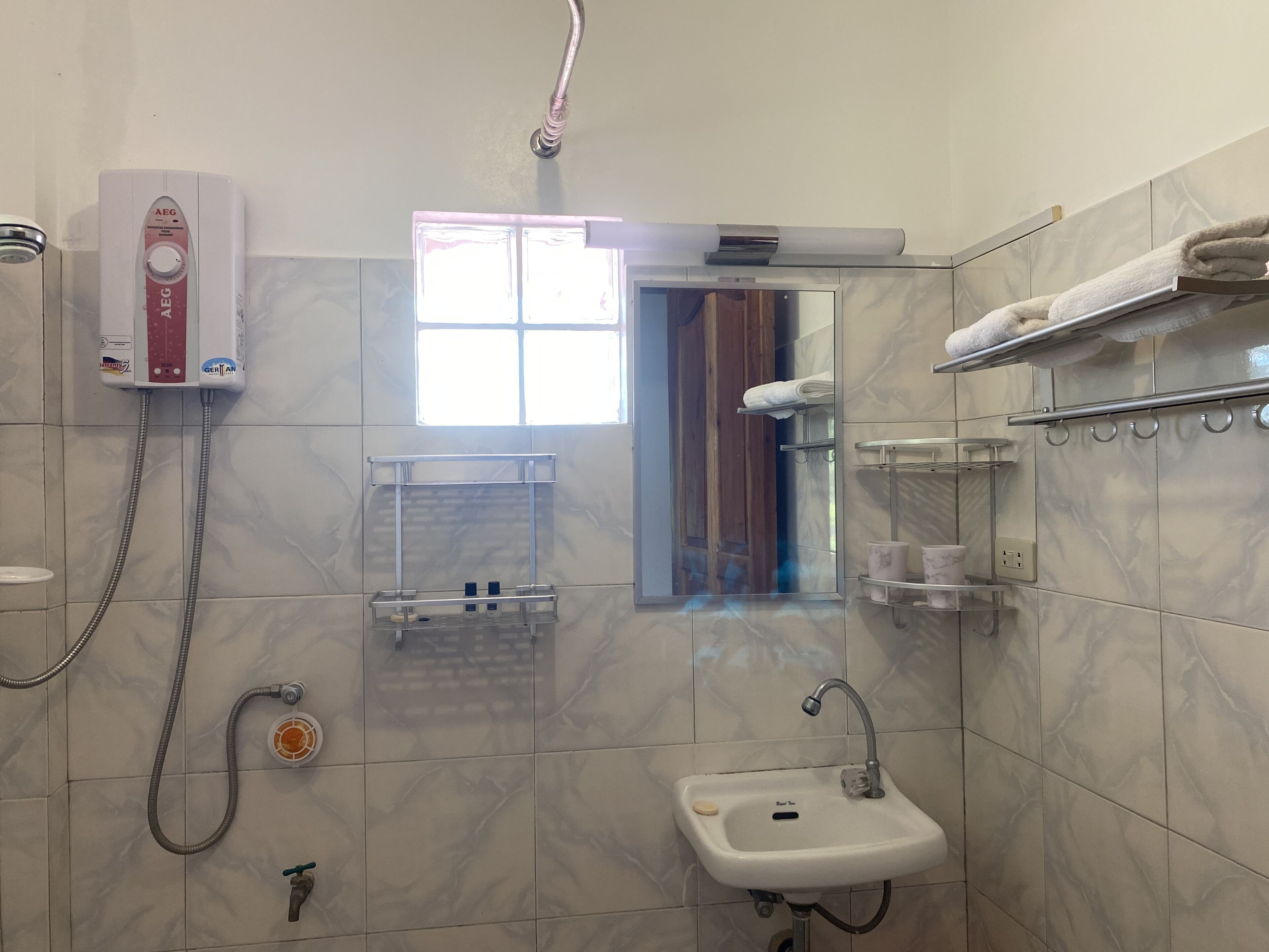 Ein Badezimmer mit Dusche, Waschbecken, Handtuchhalter und einem Fenster.