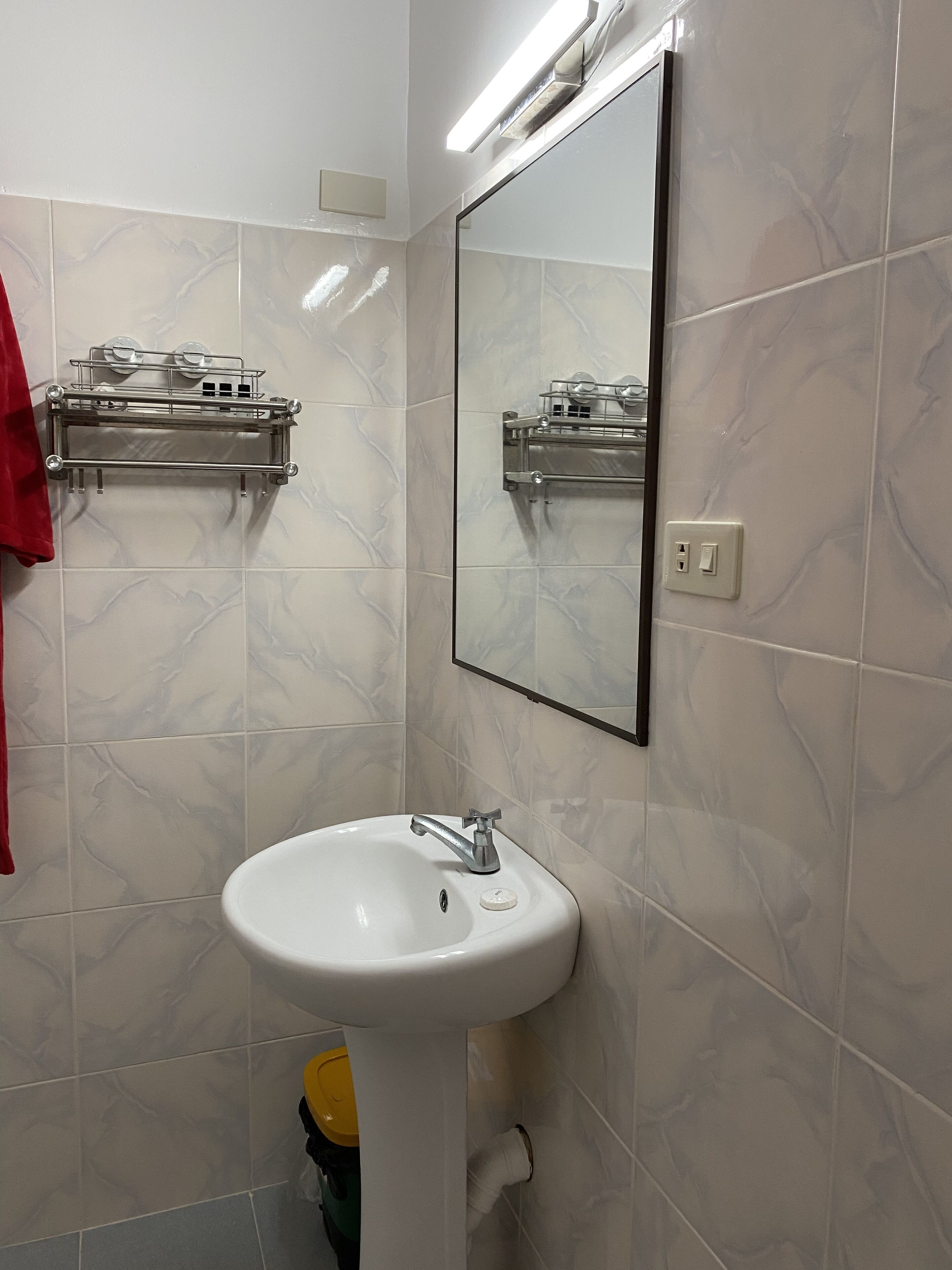 A bathroom with a white sink, a mirror, and a towel rack.