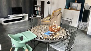 A modern living room with a round table, chairs, a sofa, a bookshelf, and a television. - LA PETITE MAISON à TARNAC en CORRÈZE (Tarnac)