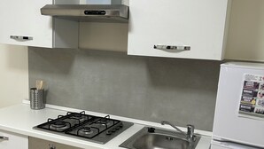 A modern kitchen with white cabinets, a gas stove, a stainless steel sink, and a built-in oven. - Vacation home located in the heart of Cilento a few steps from the sea (Centola)