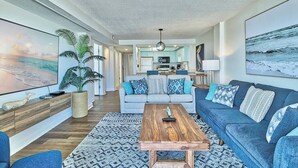 A modern living room with a sofa, coffee table, and a large TV.
