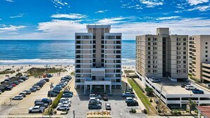 A hotel with a central atrium, parking lot, and ocean view.