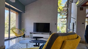 A modern living room with a large TV, a yellow chair, and a sofa.