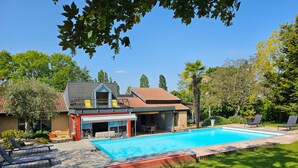A two-story house with a swimming pool, outdoor seating, and a covered patio.