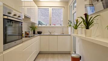 Comfort appartement | Privékeuken | Een koelkast met diepvriezer, een microgolfoven, een oven