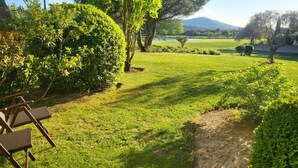 Ein gepflegter Garten mit Rasen, einigen Bäumen und weiter Aussicht auf eine ferne Bergkette.