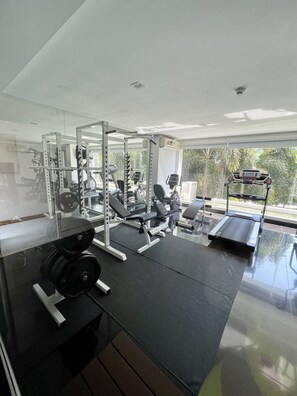 A modern gym with various exercise equipment, including a squat rack, bench press, and treadmill.