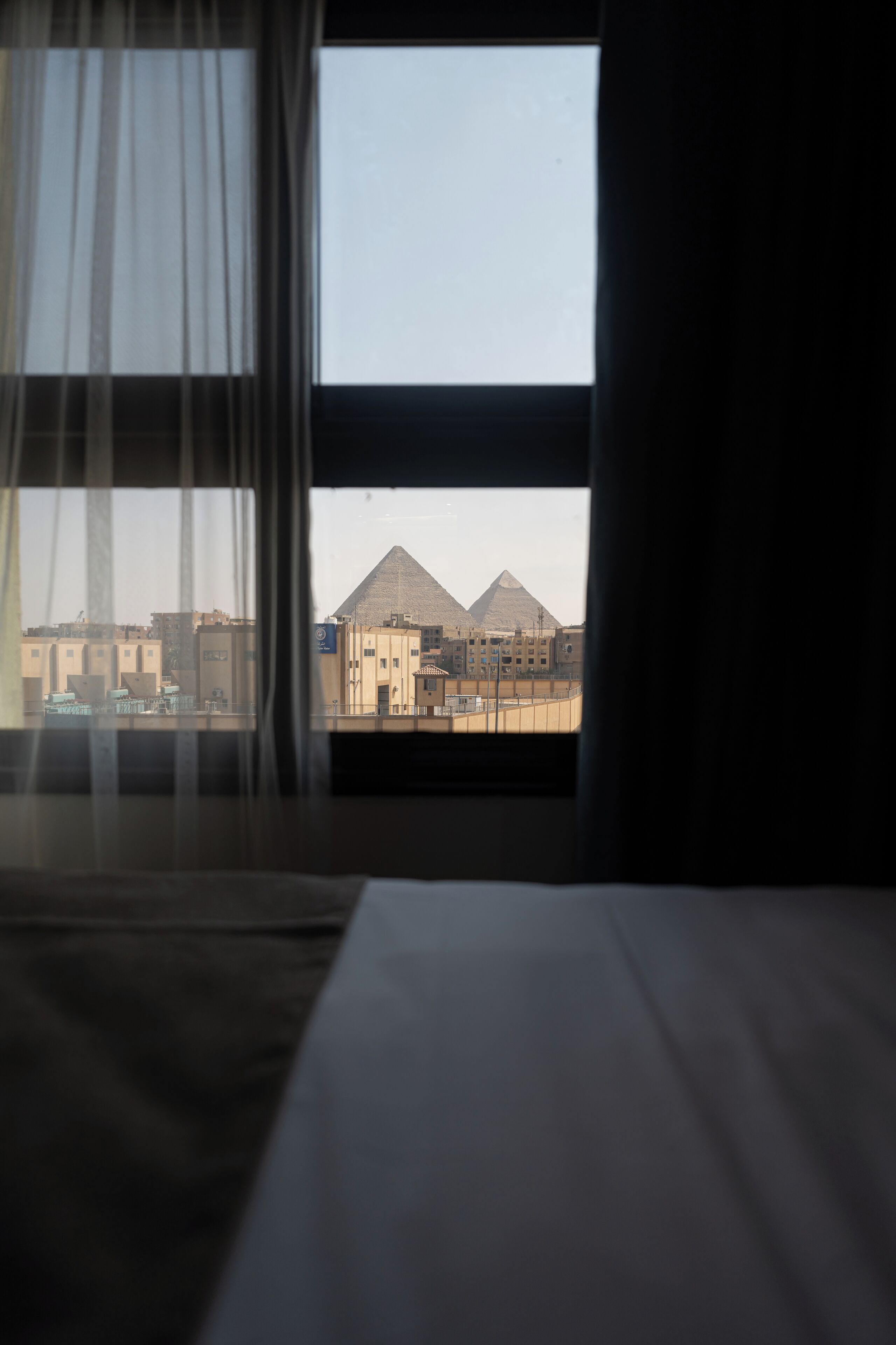 Una stanza con vista sulle piramidi, incorniciata da tende leggere.