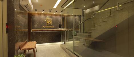 Eine moderne Lobby mit einem Marmor-Empfangsschalter, einer Glasstiege und einer Sitzecke.
