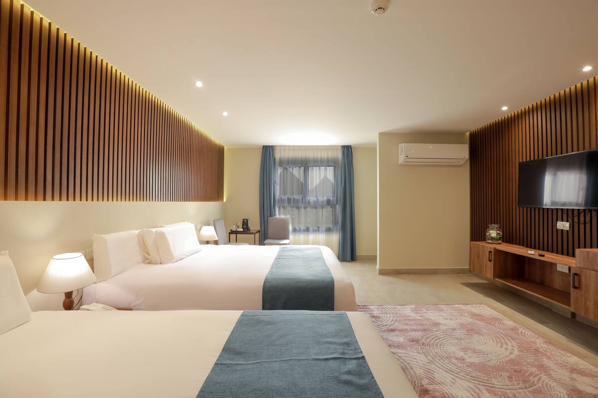Quarto de hotel com uma cama grande, televisão, escrivaninha e uma cadeira.