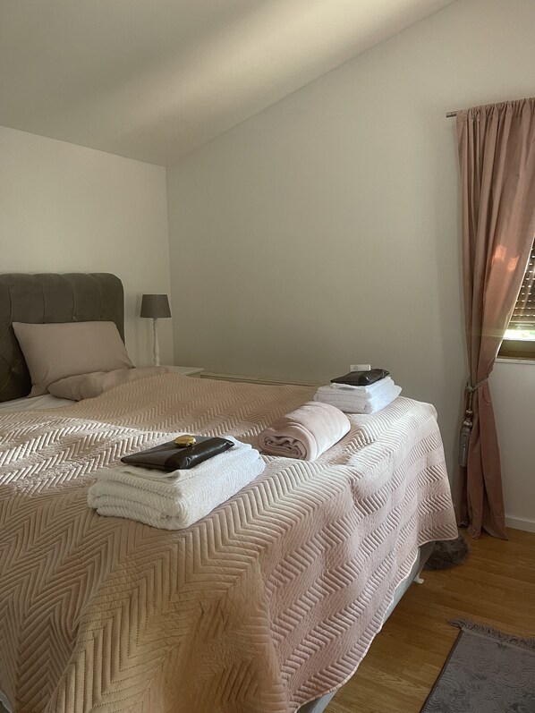 A neatly made bed with a patterned bedspread, a bedside lamp, and a window with curtains. - Weekend pool house Sarajevo with outdoor pool and fireplace in top location (Hadzici)