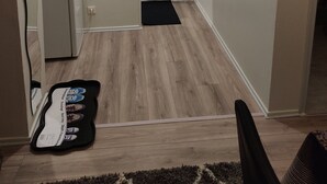 A compact living space with a refrigerator, a clock, and a small plant.