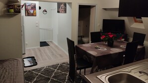 A compact kitchen with a sink, a dining area with a table and chairs, and a hallway leading to a bathroom.